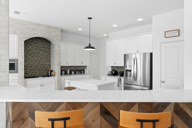 31013 Sunfall Trail Ln, Spring, TX 77386 - kitchen with stainless steel fridge, a kitchen island, decorative backsplash, black stovetop, and white cabinets