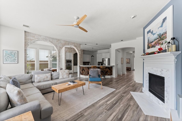 31013 Sunfall Trail Ln, Spring, TX 77386 - living area featuring a ceiling fan, arched walkways, light wood-style flooring, and a premium fireplace