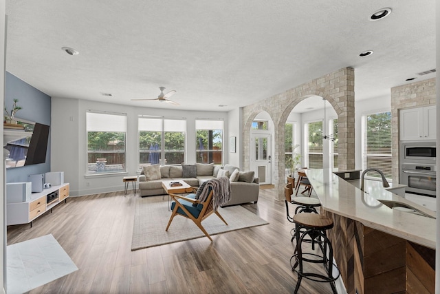 31013 Sunfall Trail Ln, Spring, TX 77386 - living area featuring arched walkways, ceiling fan, a textured ceiling, wood finished floors, and recessed lighting