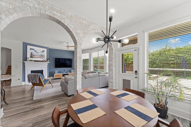 31013 Sunfall Trail Ln, Spring, TX 77386 - dining room with arched walkways, wood finished floors, a fireplace, a ceiling fan, and a chandelier