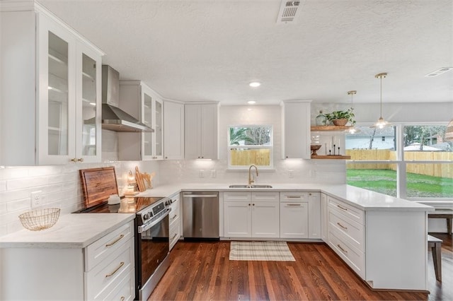 8018 Twining Oaks Ln, Spring, TX 77379 - kitchen with stainless steel appliances, wall chimney exhaust hood, a peninsula, plenty of natural light, and a textured ceiling