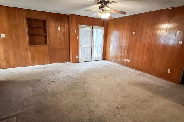 1092 S Holland St, Bellville, TX 77418 - empty room with wooden walls, built in shelves, a ceiling fan, and carpet flooring