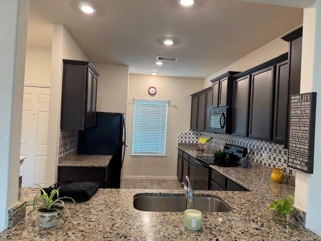 1017 Misty Patch Dr, Katy, TX 77493 - kitchen featuring black appliances, light stone countertops, backsplash, wood finished floors, and recessed lighting