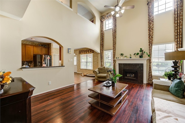18719 Glenn Haven Estates Dr, Spring, TX 77379 - living room featuring a high ceiling, a ceiling fan, wood finished floors, a fireplace, and arched walkways