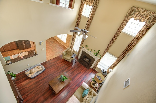 18719 Glenn Haven Estates Dr, Spring, TX 77379 - living area with a towering ceiling, a tile fireplace, wood finished floors, a ceiling fan, and arched walkways
