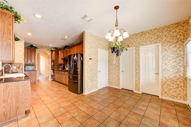 18719 Glenn Haven Estates Dr, Spring, TX 77379 - kitchen with stainless steel fridge with ice dispenser, wallpapered walls, arched walkways, light tile patterned floors, and a chandelier
