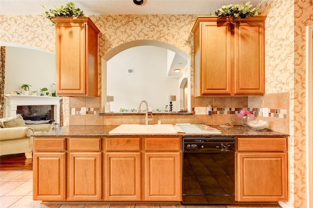 18719 Glenn Haven Estates Dr, Spring, TX 77379 - kitchen featuring dishwasher, wallpapered walls, arched walkways, a fireplace, and light tile patterned floors