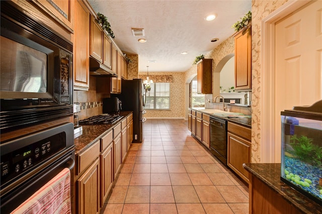 18719 Glenn Haven Estates Dr, Spring, TX 77379 - kitchen with wallpapered walls, black appliances, under cabinet range hood, light tile patterned flooring, and brown cabinetry