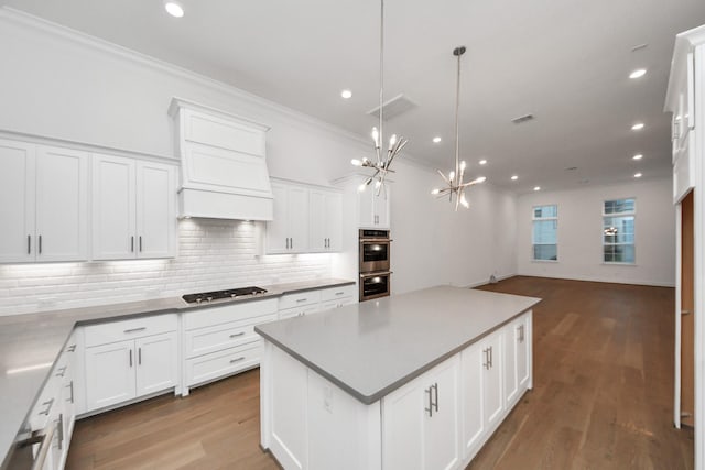 861 Dunleigh Meadows Ln, Houston, TX 77055 - kitchen with gas stovetop, ornamental molding, stainless steel double oven, a chandelier, and premium range hood