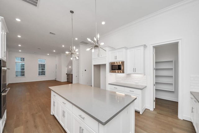 861 Dunleigh Meadows Ln, Houston, TX 77055 - kitchen featuring stainless steel microwave, a chandelier, light wood-type flooring, recessed lighting, and white cabinets