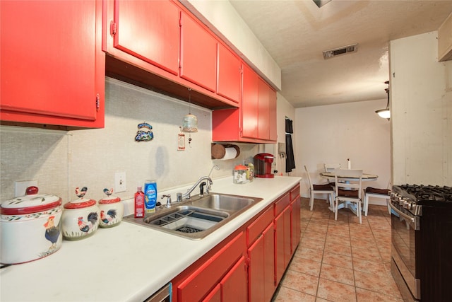 516 W Mimosa St, Angleton, TX 77515 - kitchen with stainless steel range with gas stovetop, red cabinets, light countertops, and light tile patterned flooring