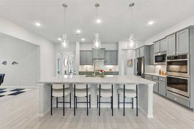 250 Peninsula Point Dr, Montgomery, TX 77356 - kitchen with appliances with stainless steel finishes, gray cabinetry, tasteful backsplash, a breakfast bar area, and recessed lighting