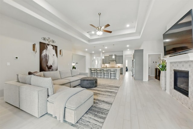 250 Peninsula Point Dr, Montgomery, TX 77356 - living area featuring ceiling fan, a tray ceiling, recessed lighting, a glass covered fireplace, and light wood-style floors