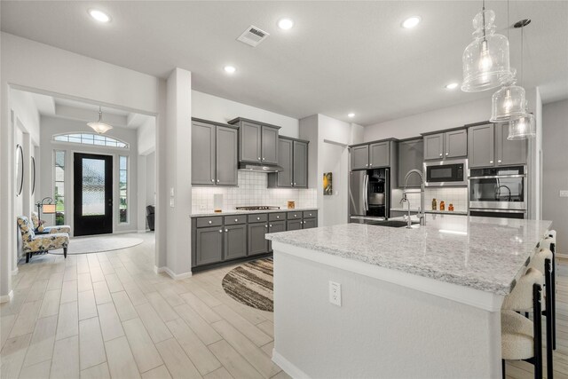 250 Peninsula Point Dr, Montgomery, TX 77356 - kitchen with appliances with stainless steel finishes, gray cabinetry, tasteful backsplash, light stone counters, and recessed lighting