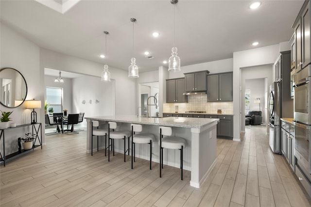 250 Peninsula Point Dr, Montgomery, TX 77356 - kitchen with stainless steel appliances, light wood-style floors, backsplash, an island with sink, and recessed lighting