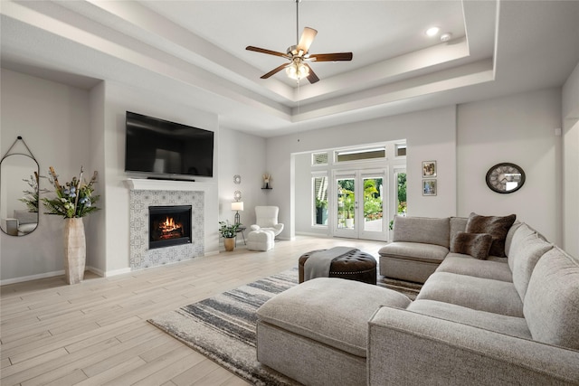 250 Peninsula Point Dr, Montgomery, TX 77356 - living area featuring a raised ceiling, a ceiling fan, a tiled fireplace, and wood finished floors