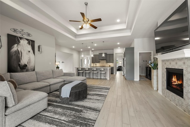 250 Peninsula Point Dr, Montgomery, TX 77356 - living room featuring ceiling fan, recessed lighting, light wood-type flooring, a raised ceiling, and a tiled fireplace