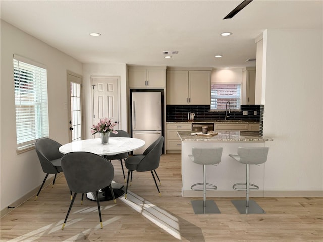5503 Duxbury St, Houston, TX 77035 - kitchen featuring freestanding refrigerator, tasteful backsplash, a kitchen bar, light wood finished floors, and recessed lighting