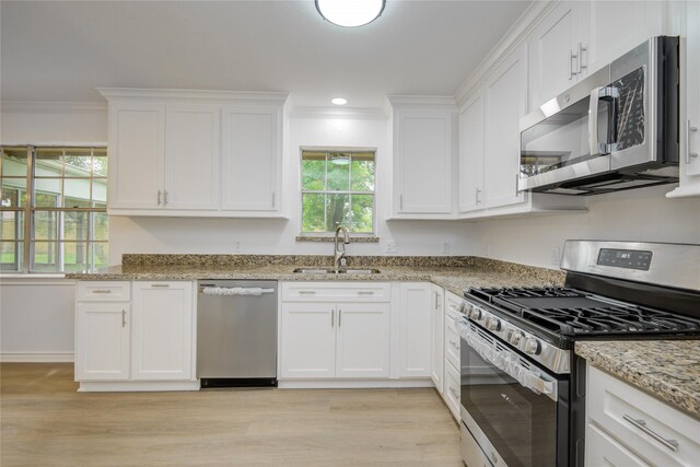 110 Spruce St, Lake Jackson, TX 77566 - kitchen with appliances with stainless steel finishes, crown molding, light wood-style flooring, white cabinetry, and light stone countertops