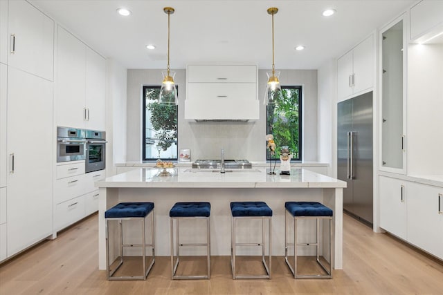 507 W Bell, Houston, TX 77019 - kitchen featuring appliances with stainless steel finishes, light wood finished floors, a breakfast bar area, and recessed lighting