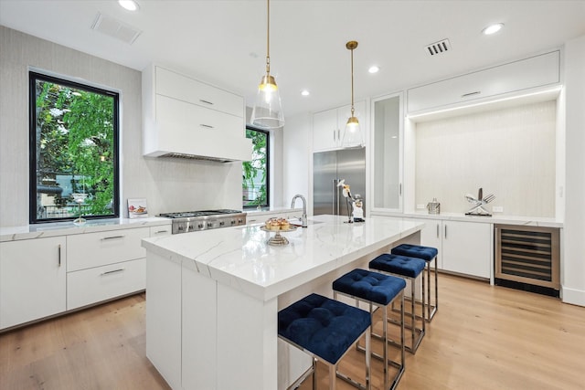 507 W Bell, Houston, TX 77019 - kitchen with wine cooler, built in fridge, light wood-style flooring, white cabinetry, and recessed lighting