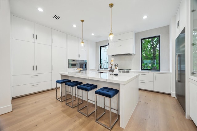 507 W Bell, Houston, TX 77019 - kitchen with light wood-style flooring, stainless steel oven, a breakfast bar area, white cabinets, and high end refrigerator