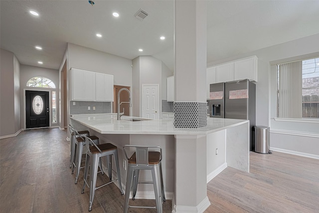7602 Las Flores Dr, Houston, TX 77083 - kitchen featuring light wood-style flooring, white cabinets, recessed lighting, stainless steel fridge with ice dispenser, and decorative backsplash