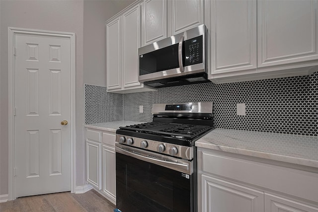 7602 Las Flores Dr, Houston, TX 77083 - kitchen with appliances with stainless steel finishes, decorative backsplash, white cabinetry, light wood-style floors, and light stone counters