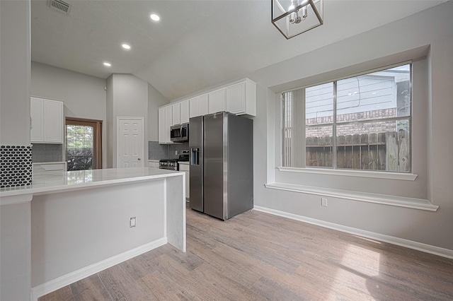 7602 Las Flores Dr, Houston, TX 77083 - kitchen with appliances with stainless steel finishes, decorative backsplash, light wood-style floors, white cabinets, and vaulted ceiling
