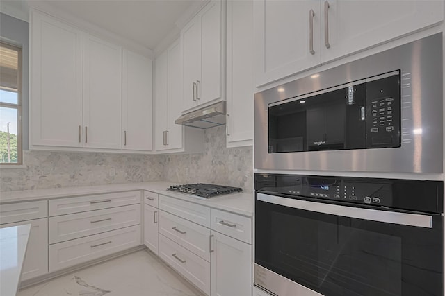 3525 Federal Rd, Pasadena, TX 77504 - kitchen with appliances with stainless steel finishes, under cabinet range hood, light marble finish flooring, white cabinetry, and light countertops