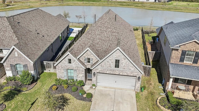 19822 Blue Roan Dr, Tomball, TX 77377 - view of front of property featuring a water view, brick siding, concrete driveway, and an attached garage