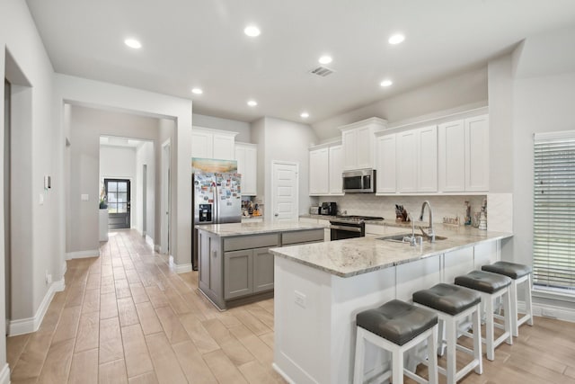 19822 Blue Roan Dr, Tomball, TX 77377 - kitchen with stainless steel appliances, backsplash, a kitchen island, light wood-style flooring, and light stone counters