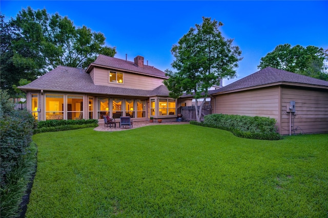 11410 Del Monte Dr, Houston, TX 77077 - back of house at dusk featuring a chimney, a sunroom, roof with shingles, and a patio area