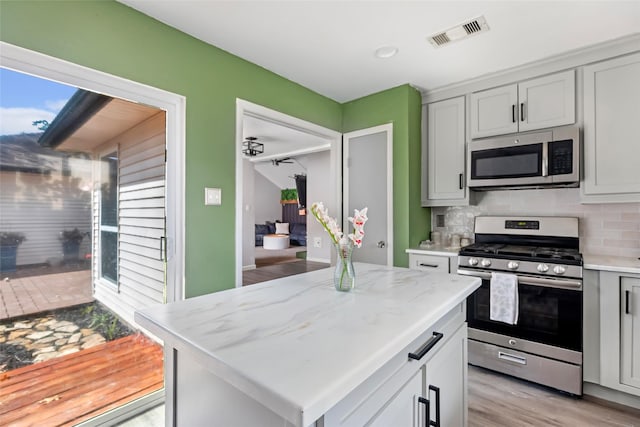 2806 Spring Dusk Ln, Spring, TX 77373 - kitchen with appliances with stainless steel finishes, tasteful backsplash, light stone countertops, and light wood-style flooring