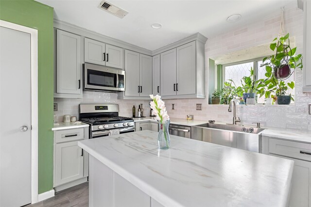2806 Spring Dusk Ln, Spring, TX 77373 - kitchen with stainless steel appliances, gray cabinetry, backsplash, and light wood-style flooring
