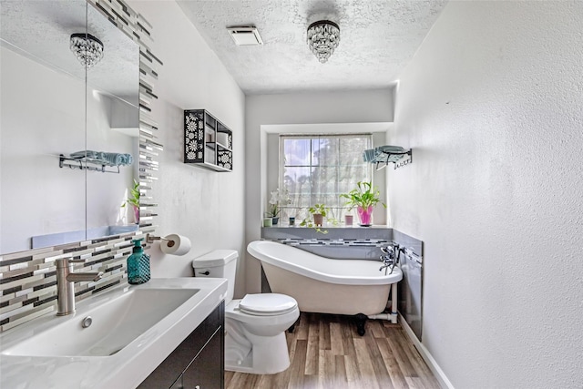 2806 Spring Dusk Ln, Spring, TX 77373 - bathroom with a textured ceiling, a freestanding bath, wood finished floors, vanity, and a textured wall
