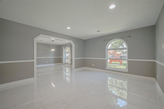 12206 Green Glade Dr, Houston, TX 77099 - empty room with light marble finish floors, arched walkways, a textured ceiling, and recessed lighting