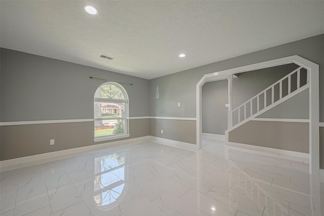 12206 Green Glade Dr, Houston, TX 77099 - empty room with marble look tiles, a textured ceiling, recessed lighting, arched walkways, and stairway