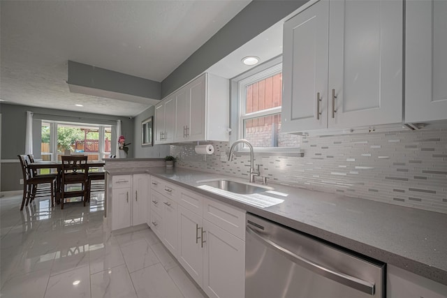 12206 Green Glade Dr, Houston, TX 77099 - kitchen featuring stainless steel dishwasher, light marble finish flooring, white cabinets, backsplash, and a peninsula