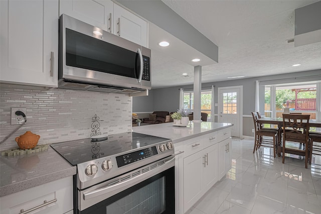 12206 Green Glade Dr, Houston, TX 77099 - kitchen featuring stainless steel appliances, light marble finish floors, tasteful backsplash, recessed lighting, and white cabinetry