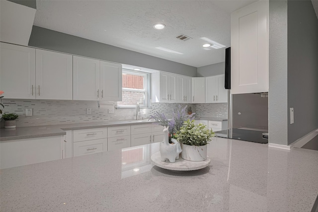 12206 Green Glade Dr, Houston, TX 77099 - kitchen featuring light stone countertops, white cabinets, decorative backsplash, a textured ceiling, and recessed lighting