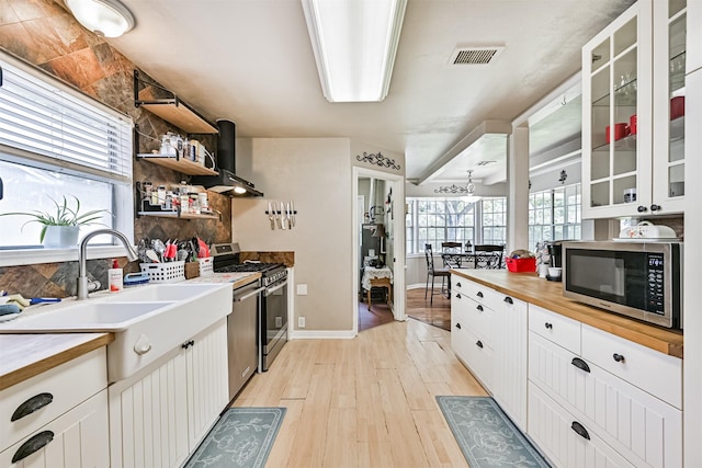 114 Wyndwood Dr, Seabrook, TX 77586 - kitchen featuring appliances with stainless steel finishes, wooden counters, wall chimney range hood, backsplash, and light wood-type flooring