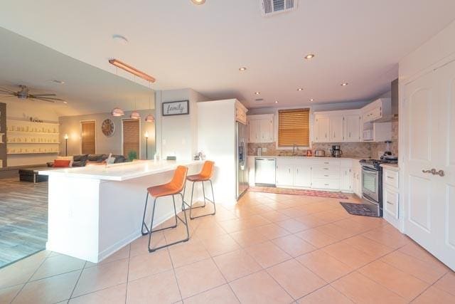 230 White Cedar St, Houston, TX 77015 - kitchen featuring appliances with stainless steel finishes, a peninsula, open floor plan, and light tile patterned floors