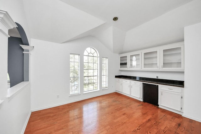 14907 Leila Oaks Cir, Houston, TX 77082 - kitchen featuring arched walkways, dark countertops, lofted ceiling, white cabinets, and glass insert cabinets