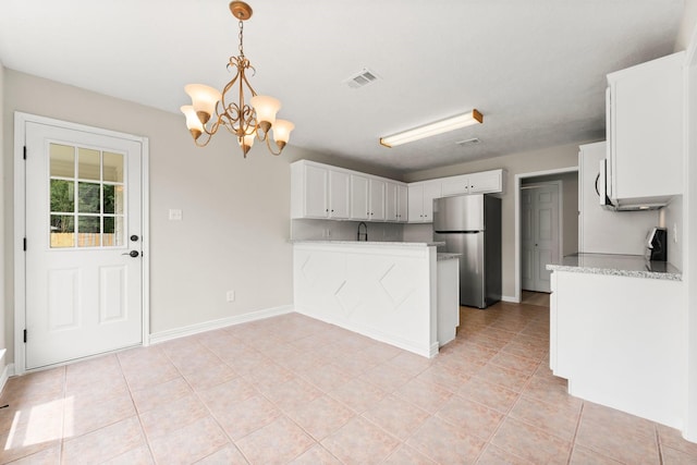 519 Tallow Dr, Conroe, TX 77385 - kitchen with freestanding refrigerator, a peninsula, white cabinets, and a chandelier