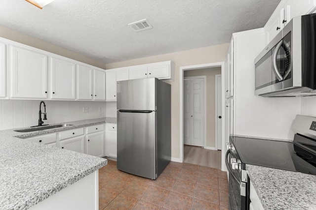 519 Tallow Dr, Conroe, TX 77385 - kitchen with stainless steel appliances, white cabinetry, tasteful backsplash, and a textured ceiling