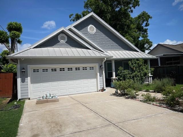 212 Greenwood St, Houston, TX 77011 - view of front of house with a standing seam roof, concrete driveway, an attached garage, and a metal roof