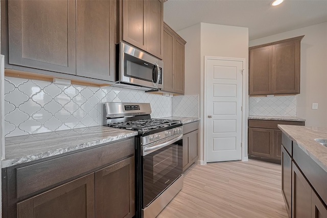 27302 Blue Pool Dr, Katy, TX 77493 - kitchen with appliances with stainless steel finishes, light wood-style floors, light stone countertops, tasteful backsplash, and recessed lighting