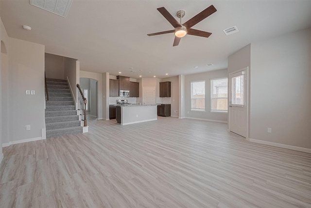 27302 Blue Pool Dr, Katy, TX 77493 - unfurnished living room featuring a ceiling fan, stairway, light wood finished floors, arched walkways, and recessed lighting