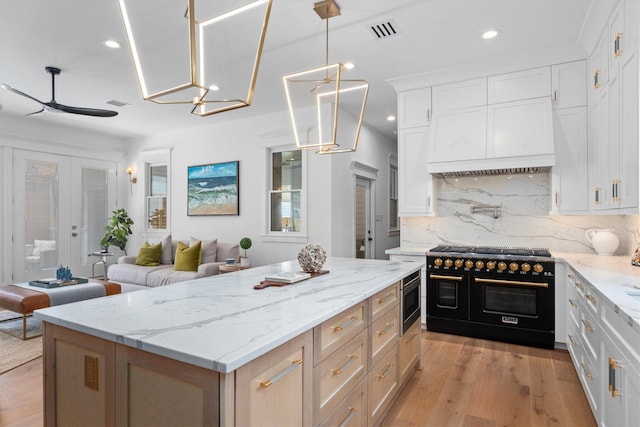 1543 Columbia St, Houston, TX 77008 - kitchen featuring double oven range, a center island, stainless steel microwave, decorative backsplash, and light wood-style floors